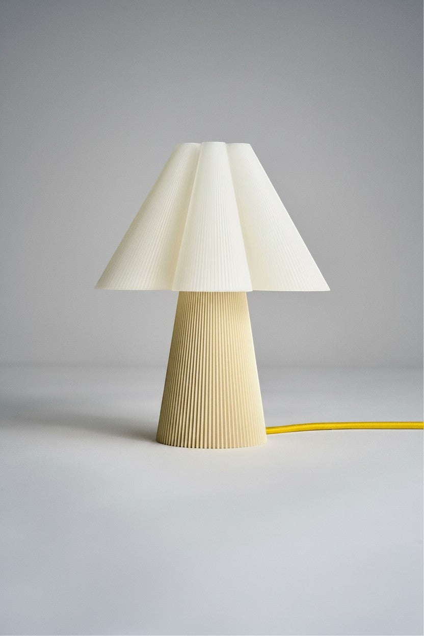 Layerd Bloom Chalk table lamp with pleated cream shade and conical base, yellow cord.